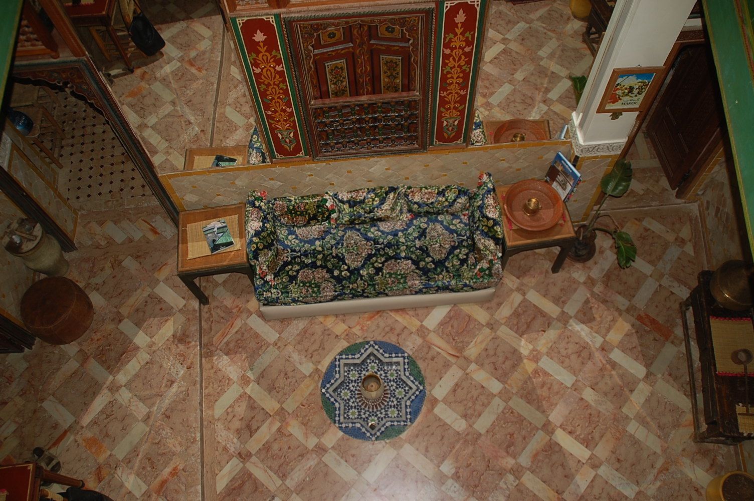 Une pièce avec un tapis à motifs, un canapé, un tapis décoratif et un sol carrelé.