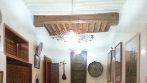 A traditional interior with patterned flooring, wooden furniture, and decorative wall hangings. - Museum House - Dar Melyani (Fes)