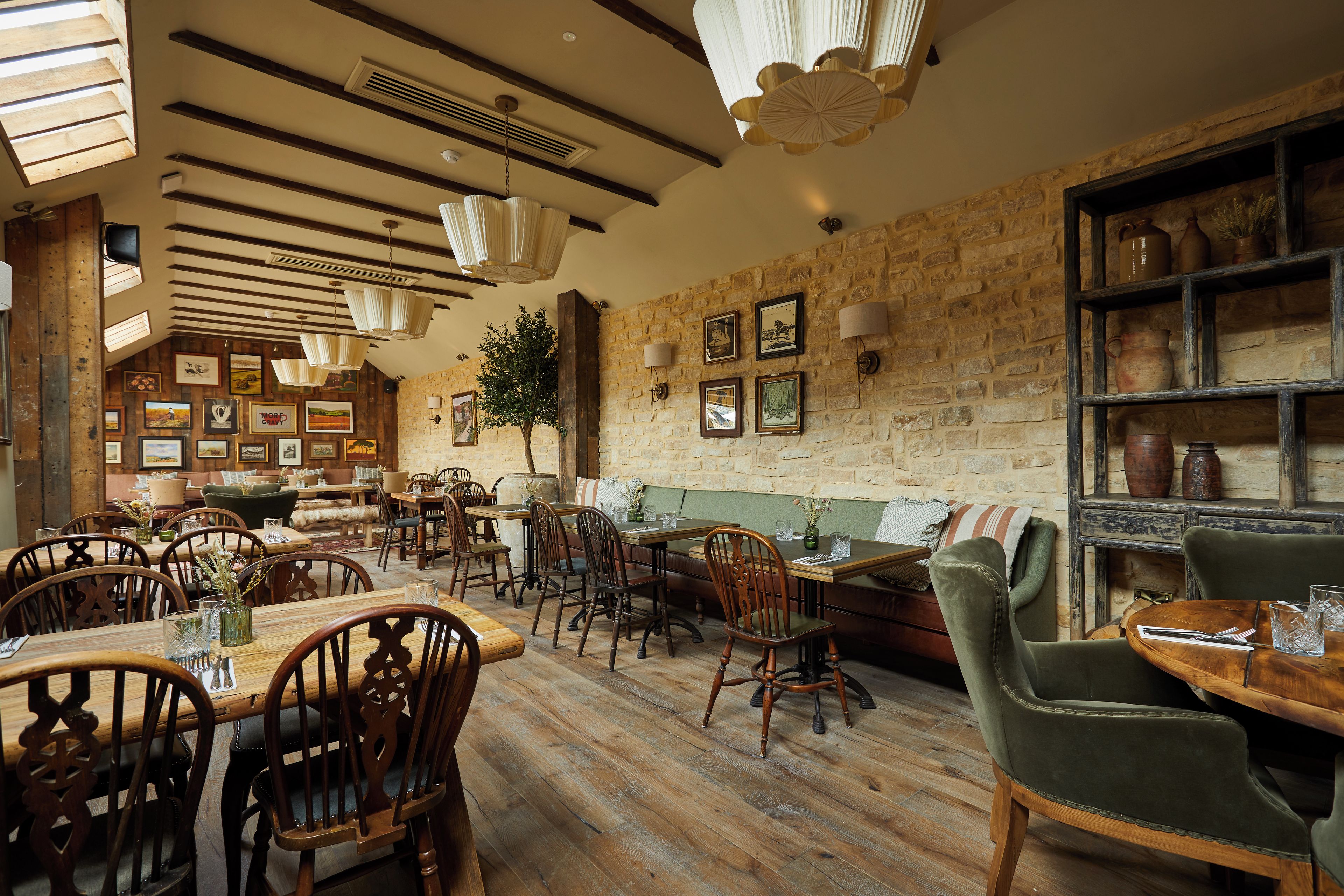 Un interior rústico con muebles de madera, paredes de piedra y varias obras de arte enmarcadas.
