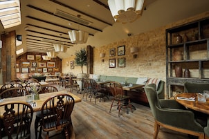 Un interior rústico con muebles de madera, paredes de piedra y varias obras de arte enmarcadas.