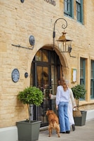 Un edificio de piedra con un cartel que dice 'PUB & DINING' y un perro parado afuera.