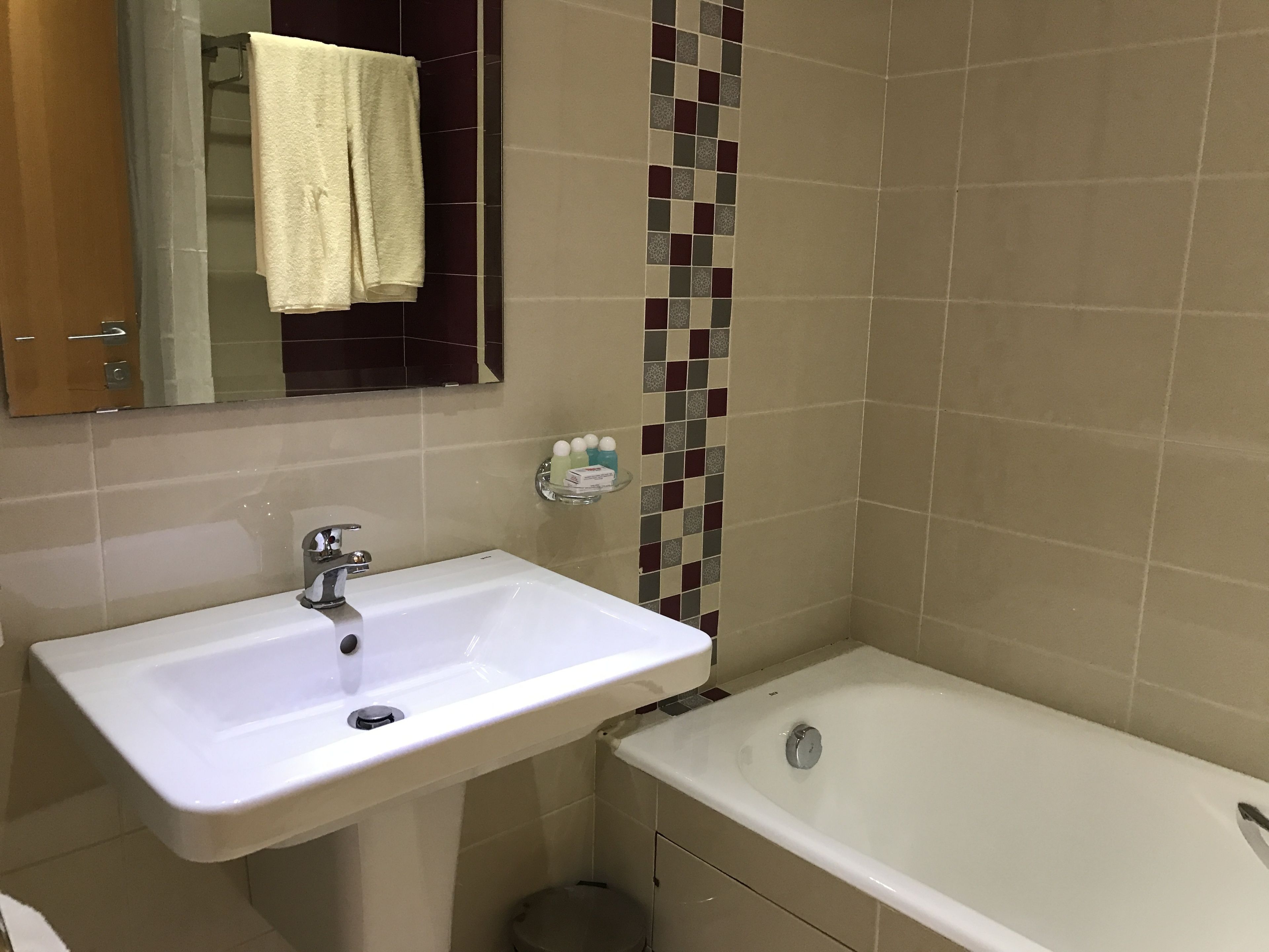 Un baño con un lavamanos blanco, una bañera y un espejo sobre el lavamanos.