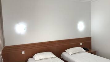 Ein Hotelzimmer mit zwei Einzelbetten, Holz-Kopfteilen und Nachttischen.