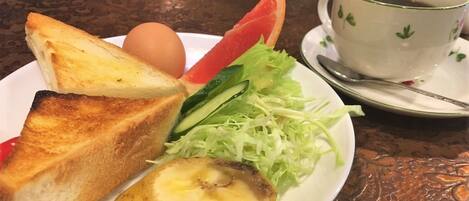A plate with toast, a boiled egg, a slice of watermelon, and shredded lettuce.