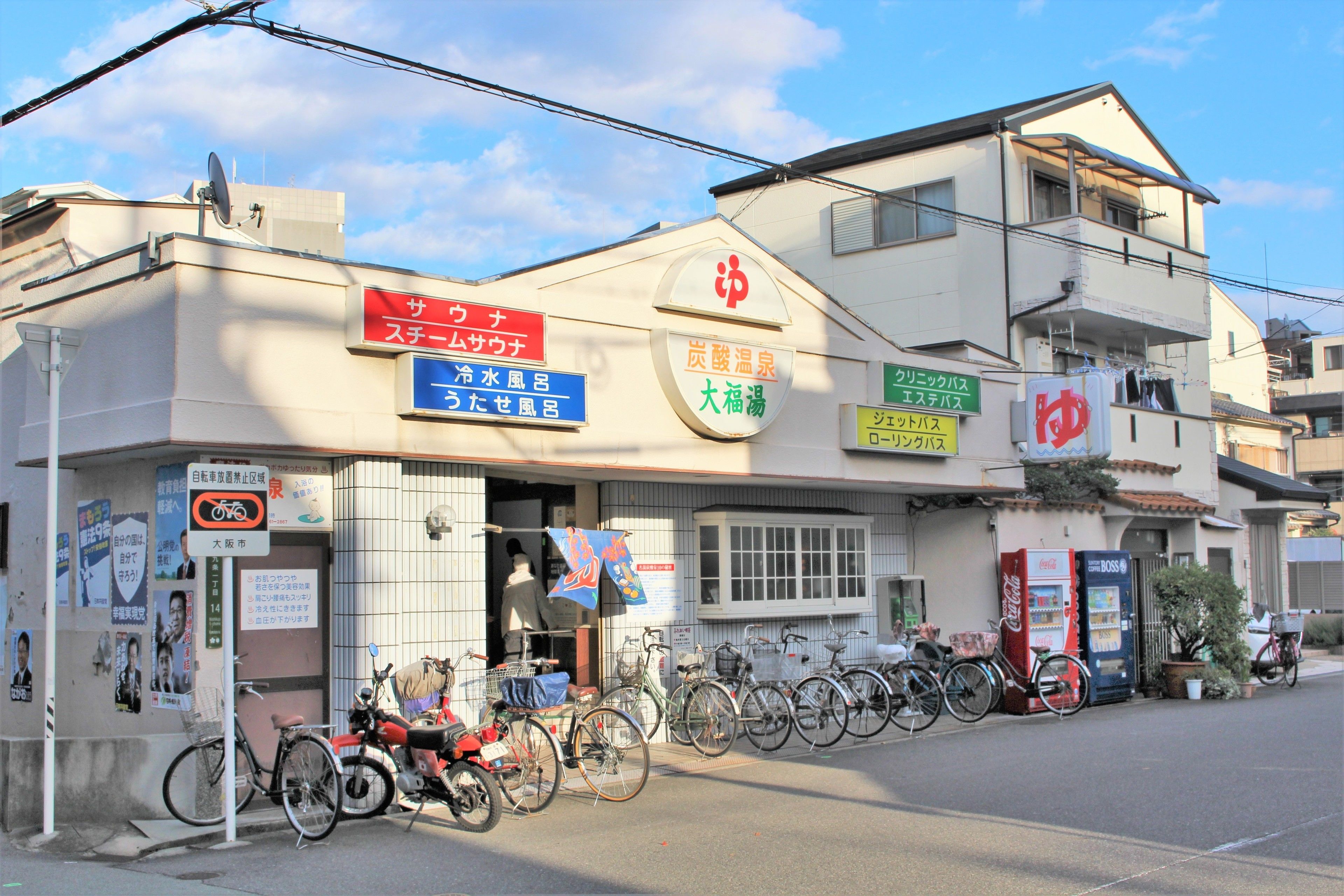 A building with multiple signs, including one for a hot spring and another for a bicycle rental service.