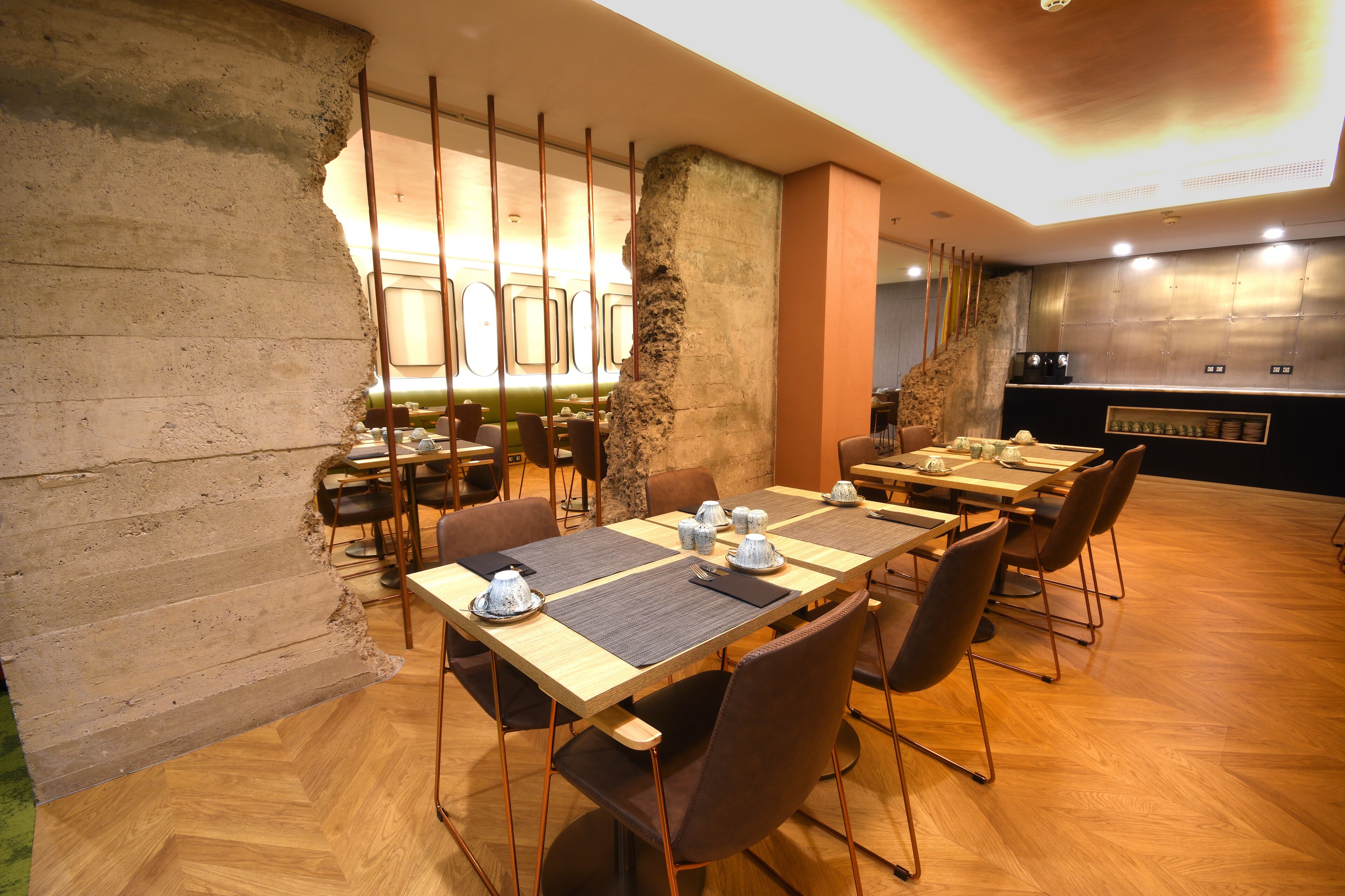 Un restaurante con decoración rústica, que presenta paredes de concreto a la vista, suelo de madera y una disposición de asientos moderna.