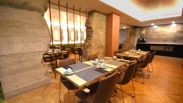 Un restaurante con decoración rústica, que presenta paredes de concreto a la vista, suelo de madera y una disposición de asientos moderna.