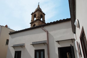 Un edifici amb una torre campanar, finestres i una canonada visible.