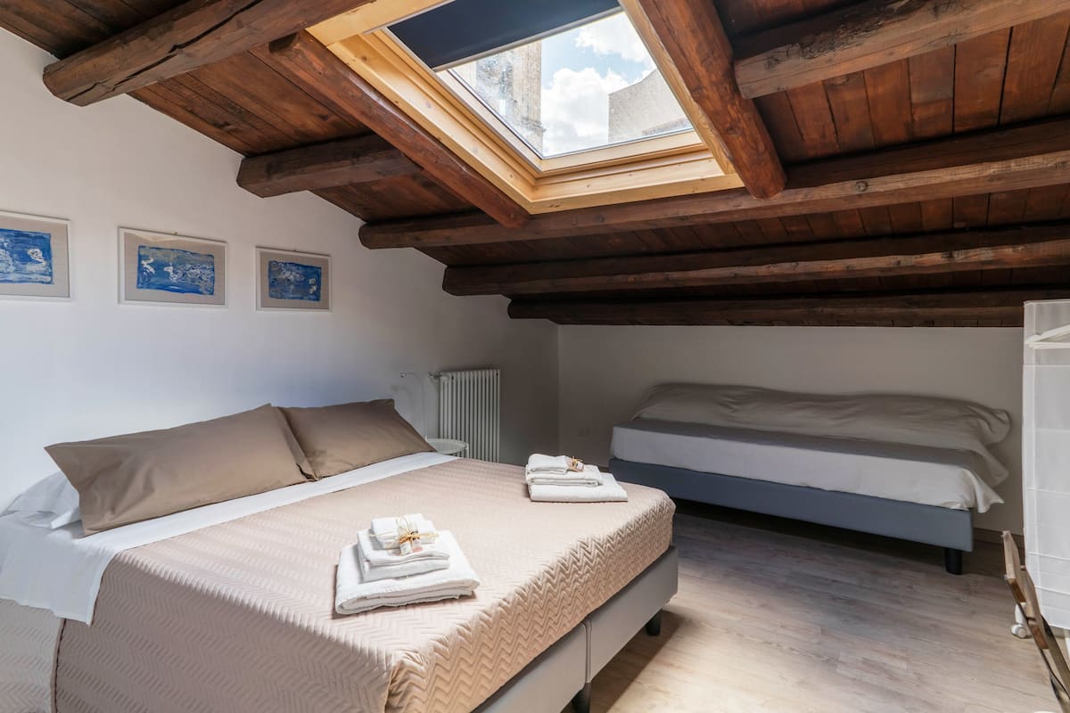 Quarto com claraboia, duas camas e obras de arte na parede.