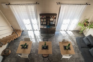 Un saló modern amb una escala, una biblioteca i dues taules amb plantes en testos.