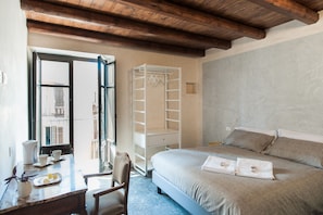 Un dormitorio con cama, armario, escritorio y silla, y una ventana.