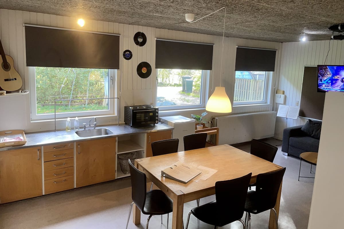 A compact kitchen with a dining area, large windows, and a television.