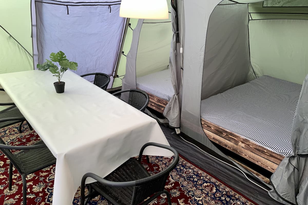 A tent with a bed, a table, and chairs.