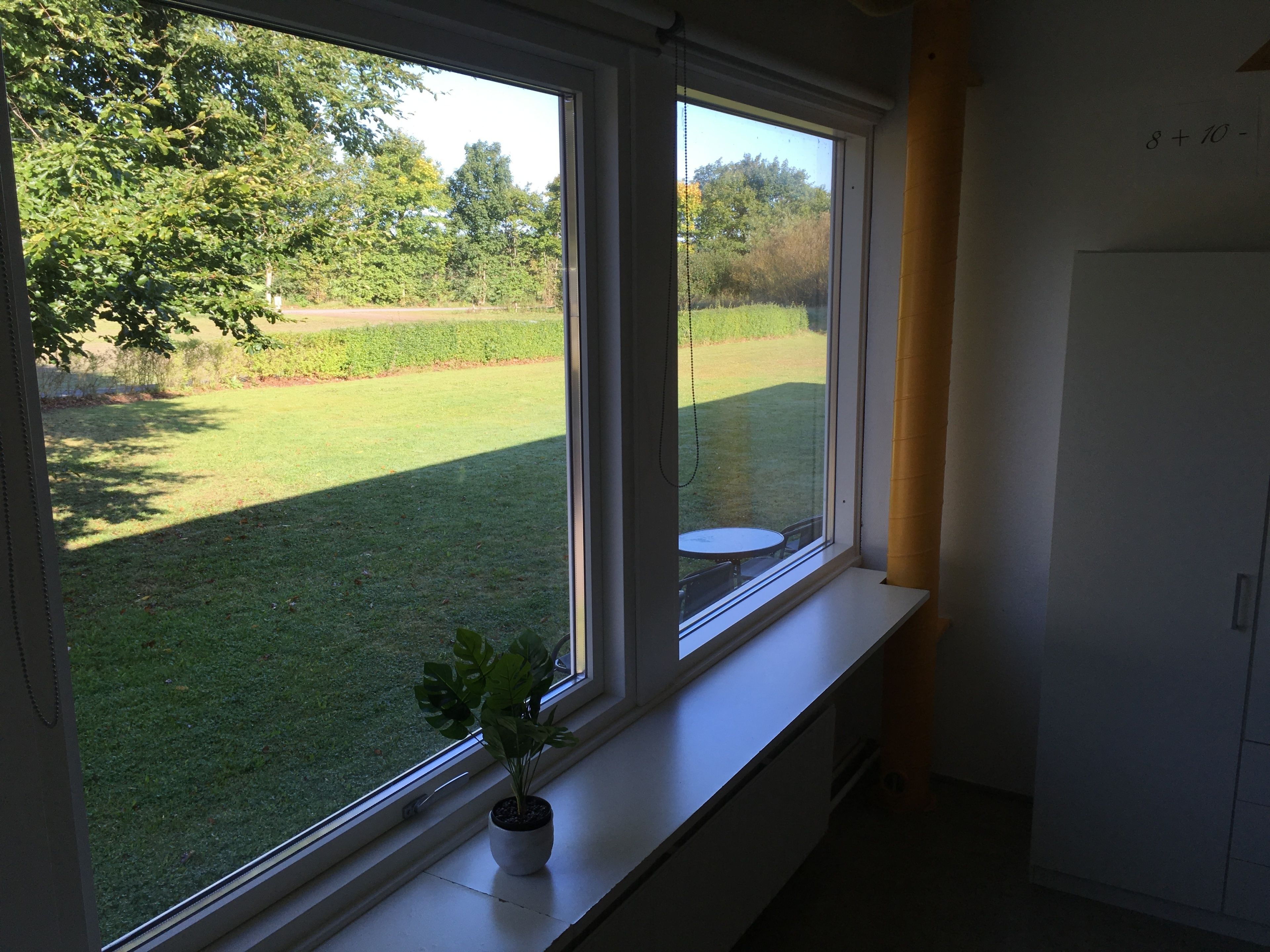 A room with a large window overlooking a grassy yard.