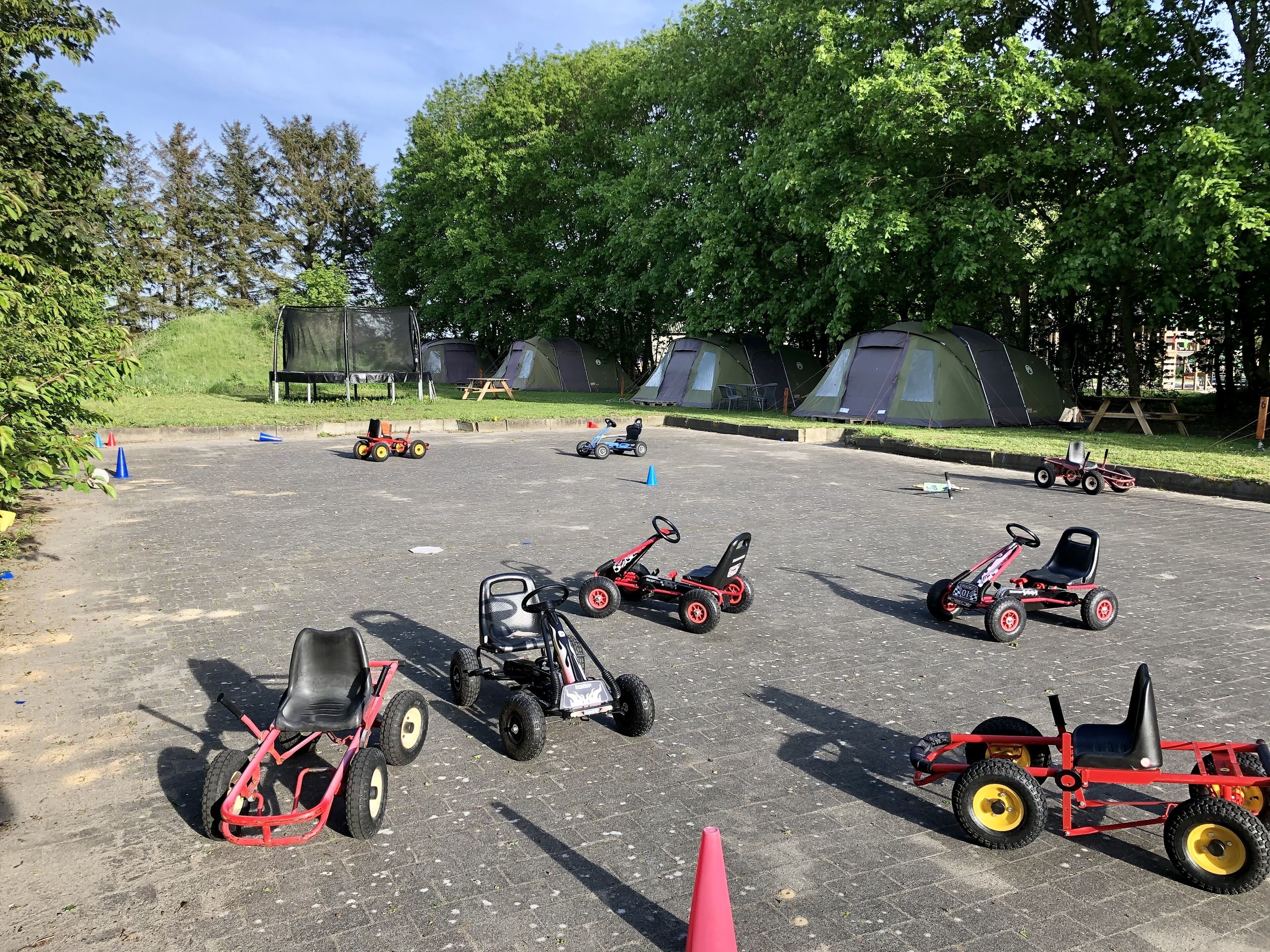 A parking lot with several go-karts and tents in the background.