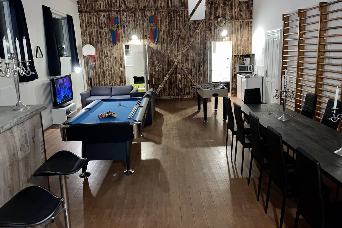 A room with a pool table, a foosball table, a bar area, and a cozy seating area.