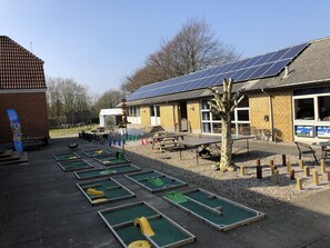 A building with solar panels, outdoor tables, and a bowling alley. - Hestkær Family Rooms (Grindsted)