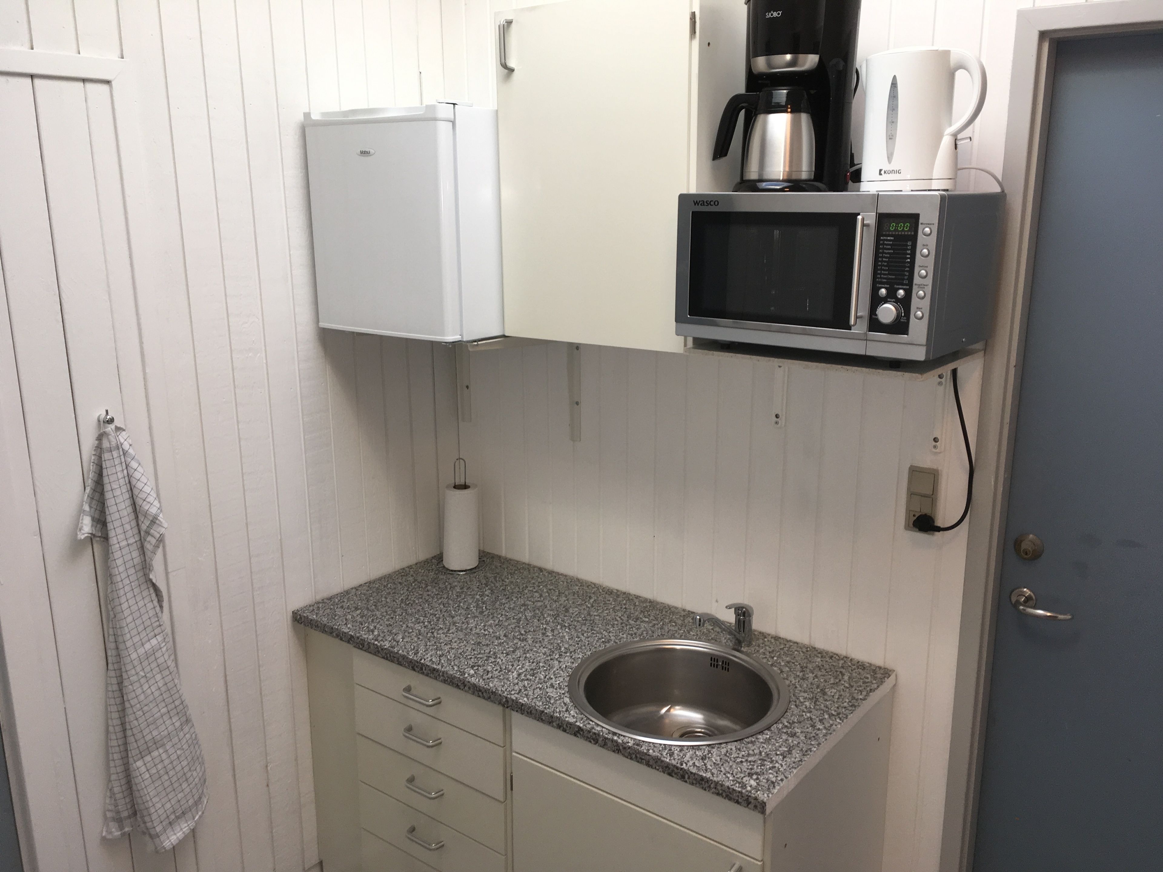 A compact kitchen with a sink, a microwave, and a coffee maker.