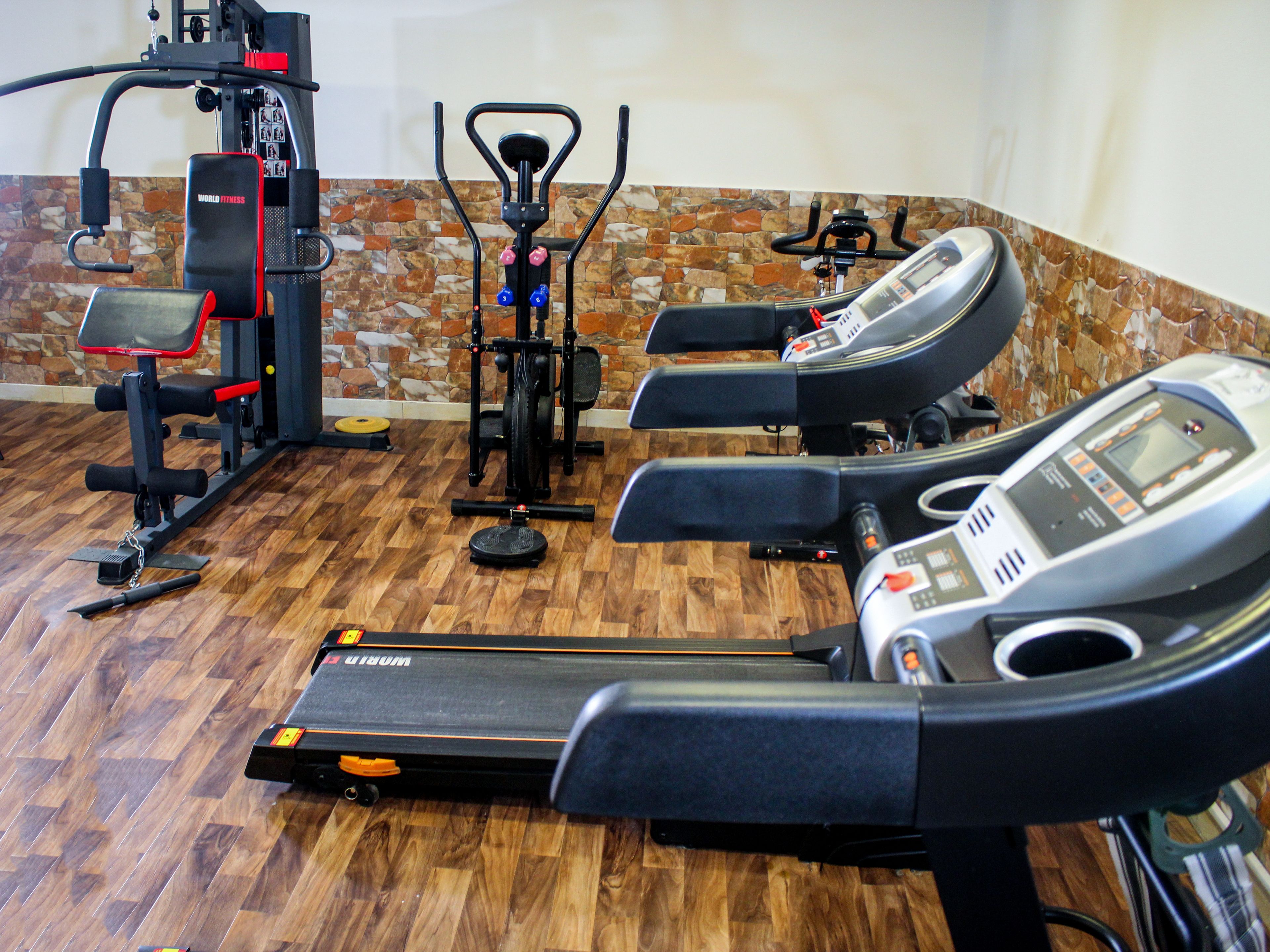Un gimnasio con cintas de correr, una bicicleta estática y una máquina de pesas.