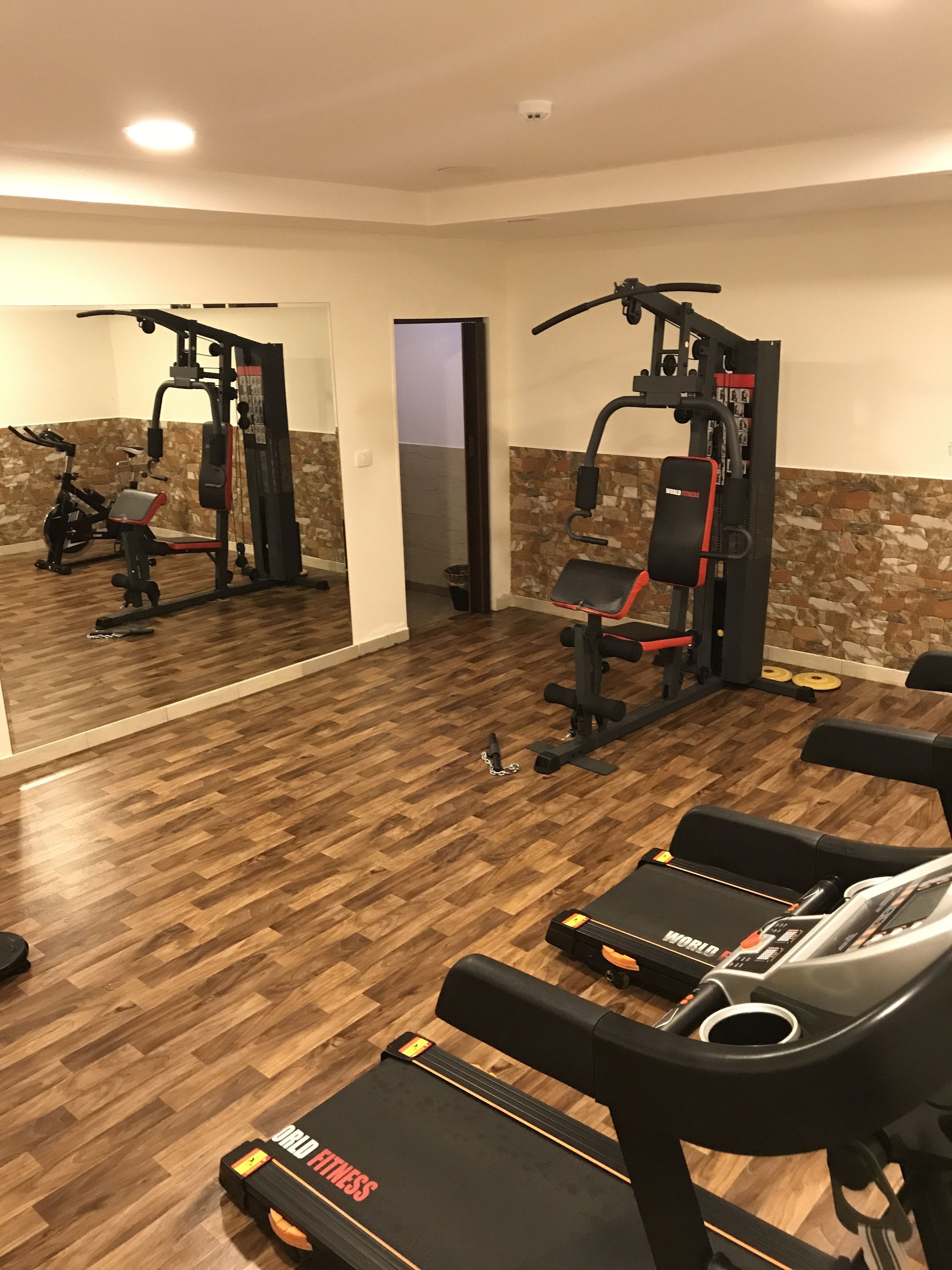 Une salle de sport à domicile équipée d’un tapis de course, d’un banc de musculation et de divers appareils d’exercice.