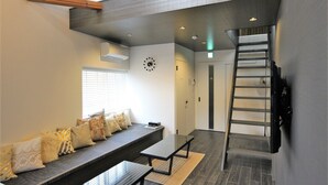 Ein modernes Interieur mit einer Sitzbank, einer Leiter und einer Treppe, die in ein weiteres Geschoss führt.