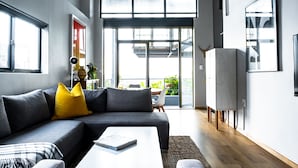 A modern living room with a grey sectional sofa, a white coffee table, and a yellow throw pillow.