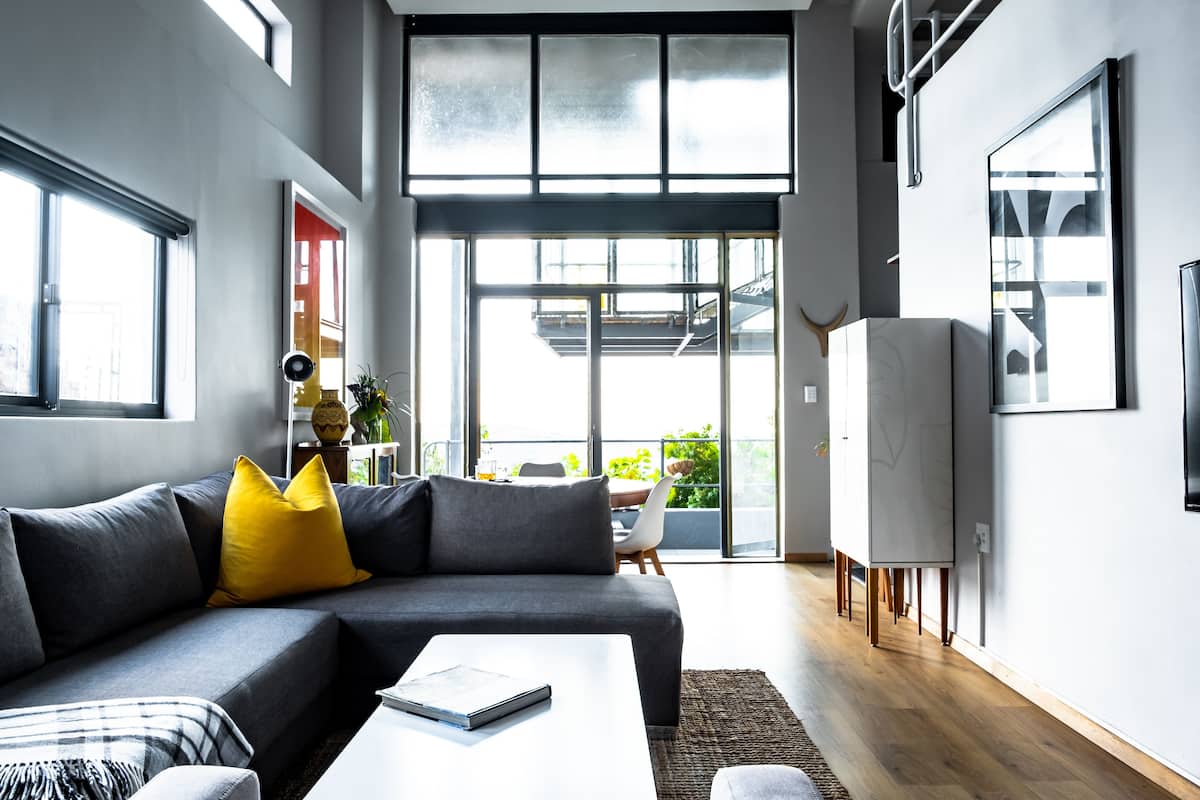 A modern living room with a grey sectional sofa, a white coffee table, and a yellow throw pillow.