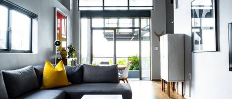 A modern living room with a grey sectional sofa, a white coffee table, and a yellow throw pillow.