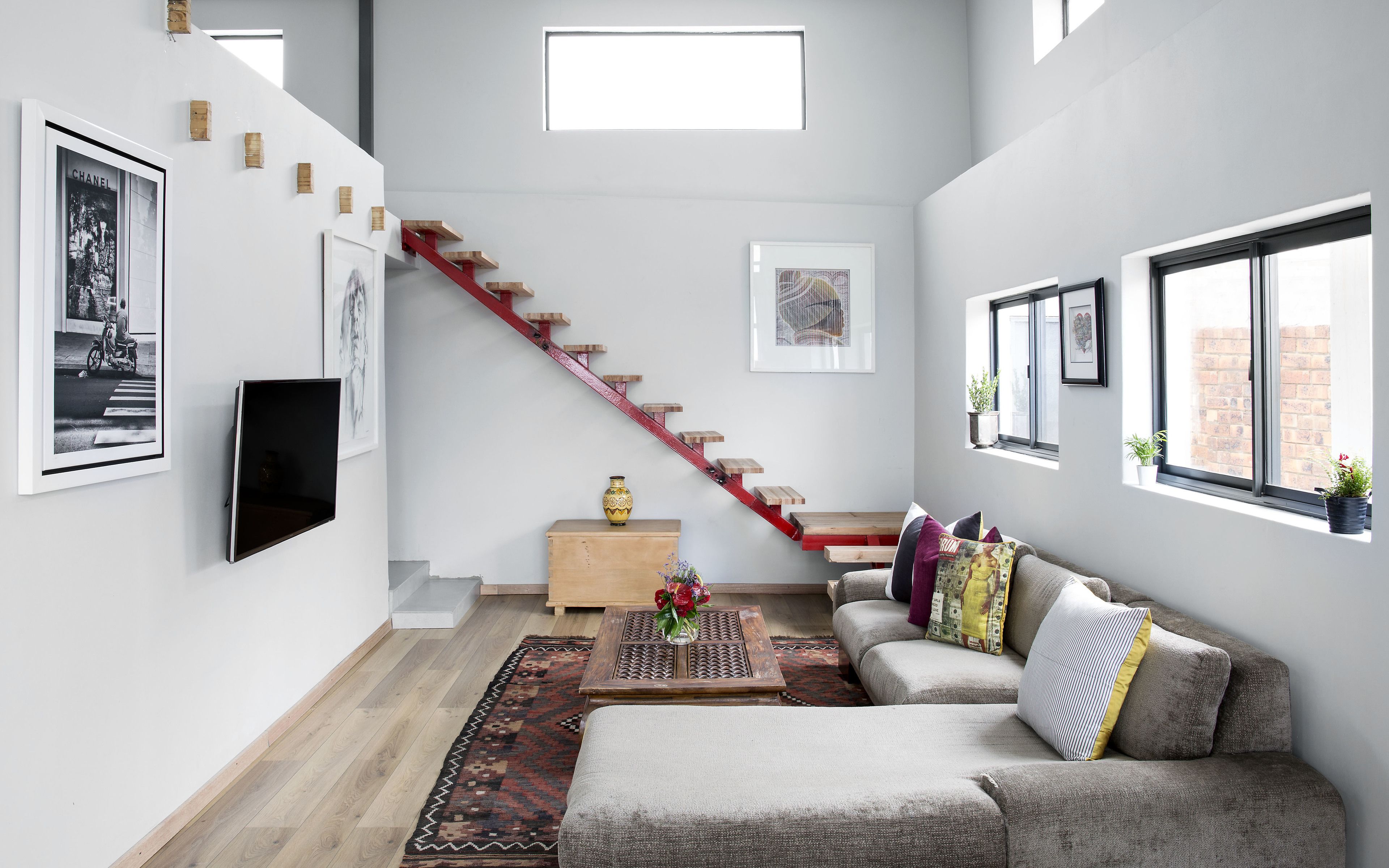 Een moderne woonkamer met een trap, een bank, een salontafel en kunstwerken aan de muren.