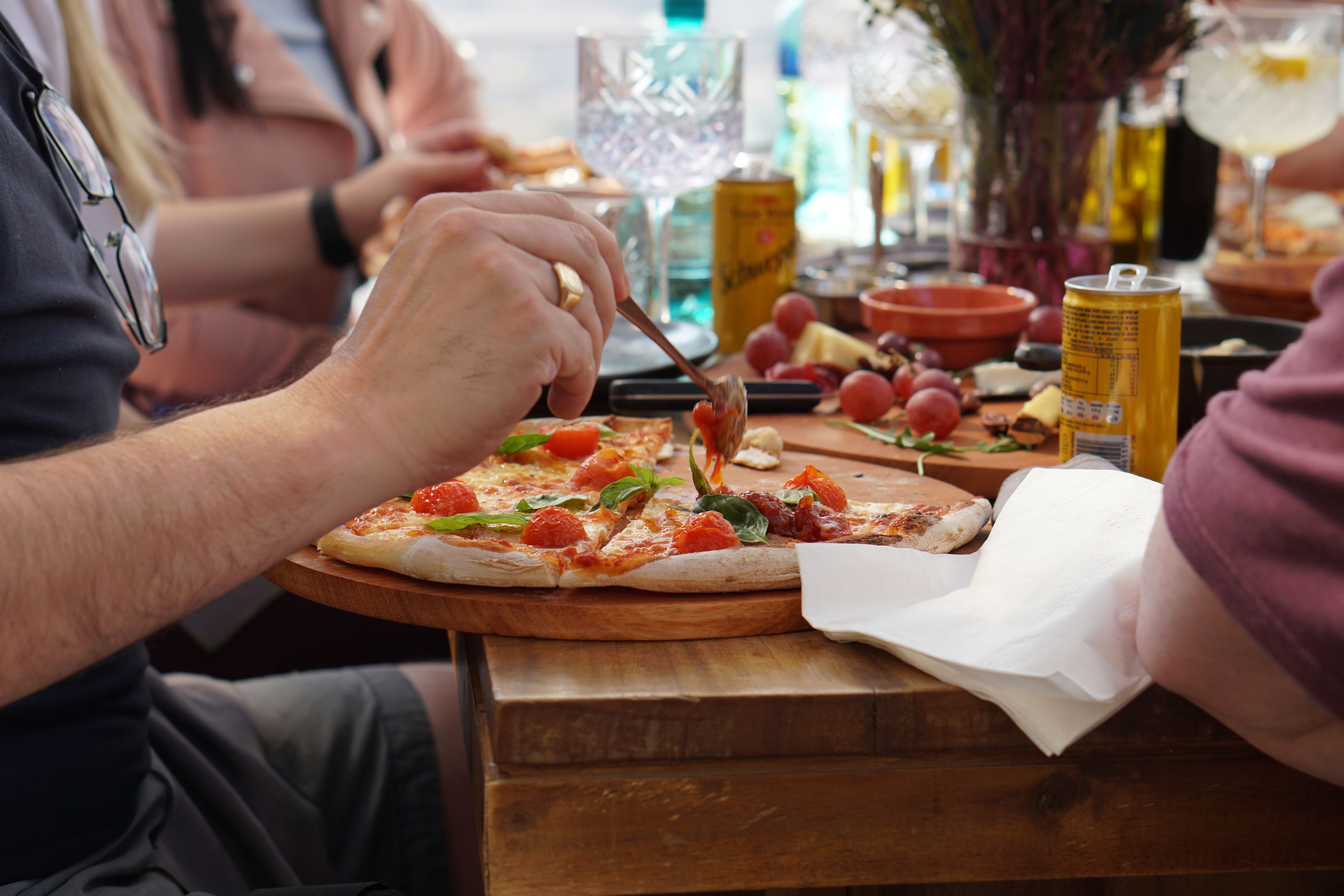 A person cutting a pizza on a wooden board.