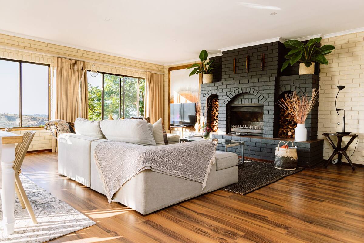 A modern living room with a fireplace, a sofa, and a large window.