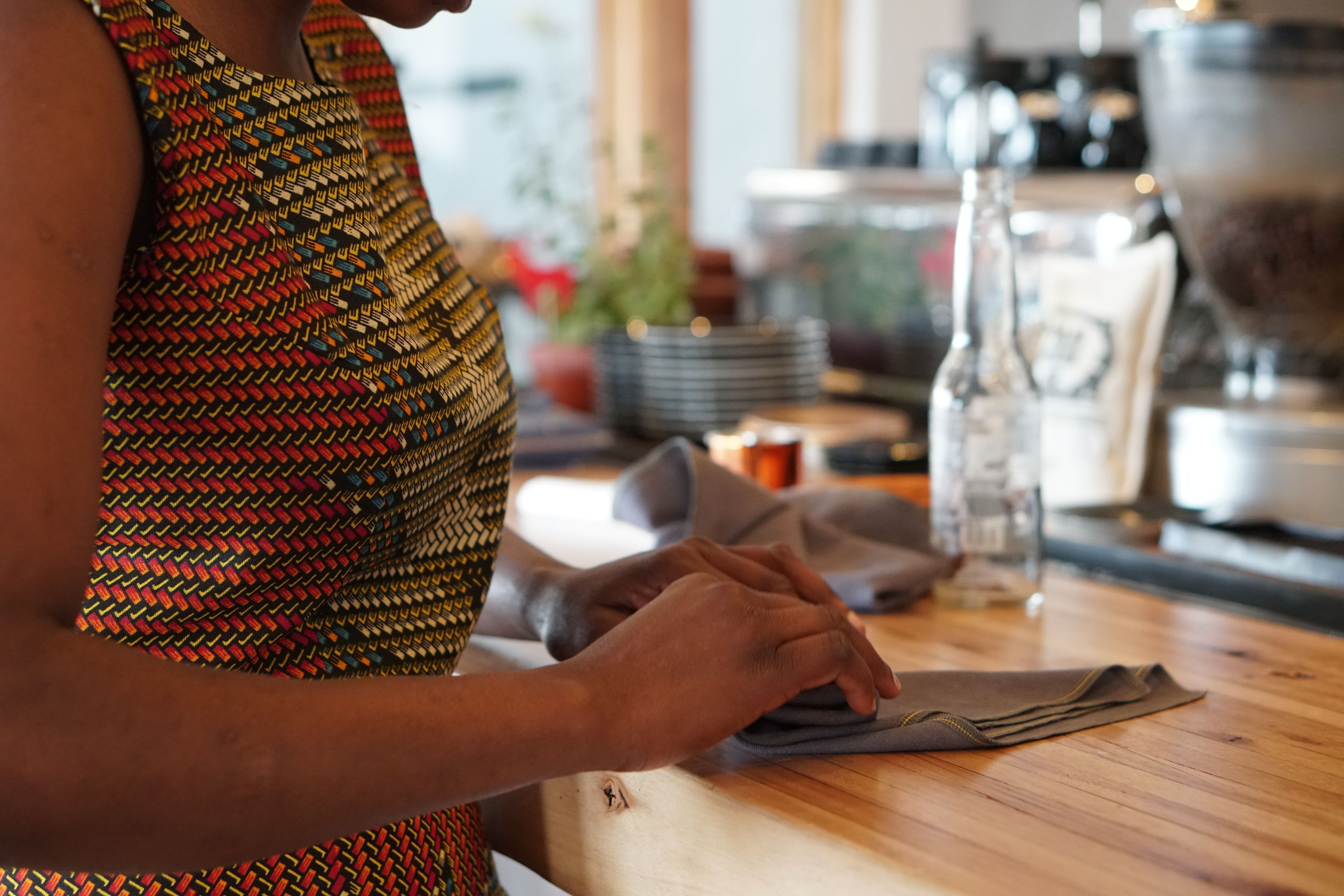 A person folding a garment on a wooden table in a kitchen setting.