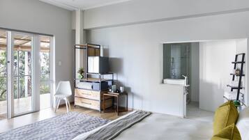 Quarto moderno com cama grande, escrivaninha, cadeira, guarda-roupa, televisão e banheiro com espelho e pia.