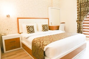 Una cama bien hecha con cabecera, una mesita de noche con cajones, una lámpara y una ventana con cortinas.