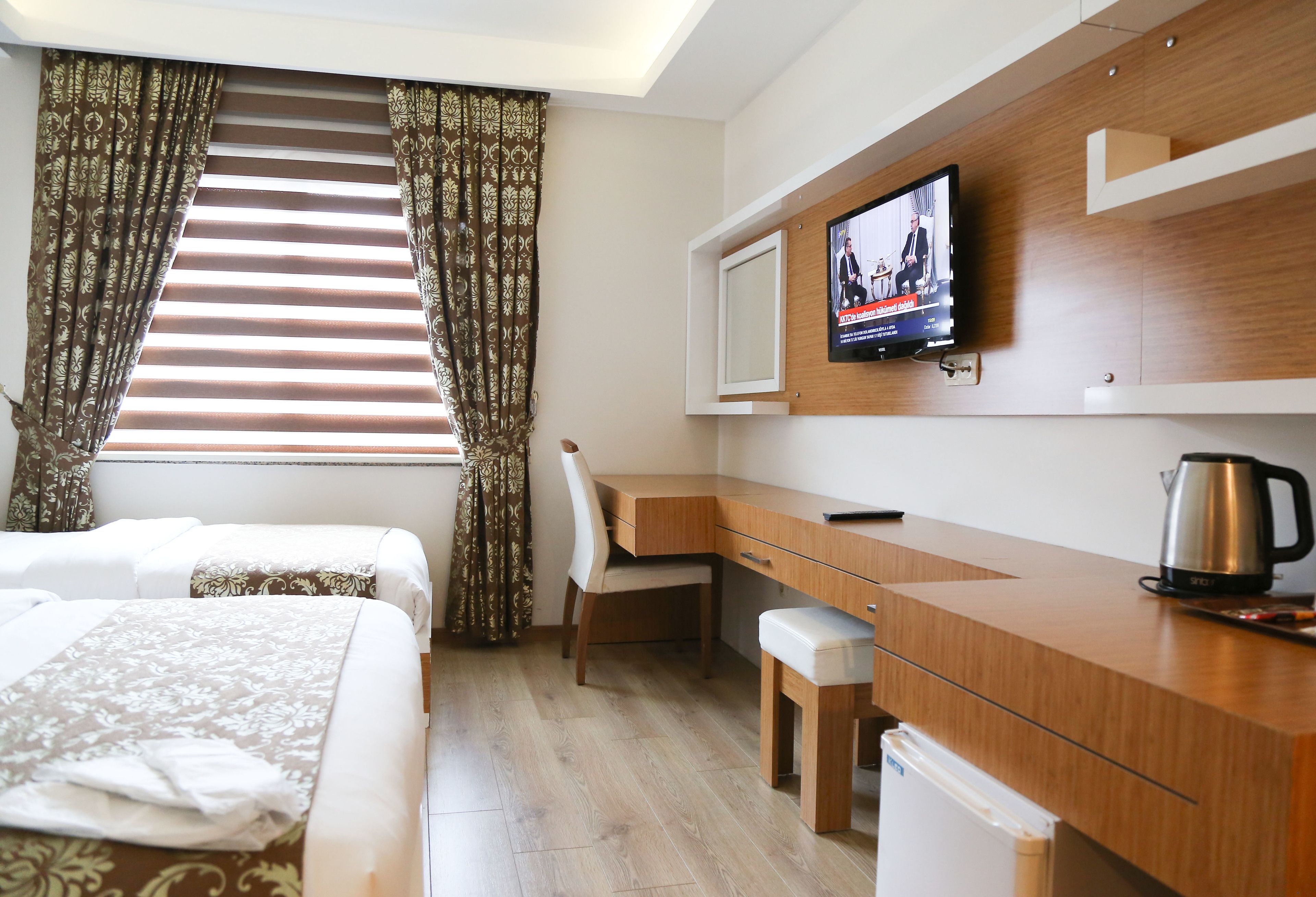 Een hotelkamer met een bed, bureau, stoel, televisie en koffiezetapparaat.