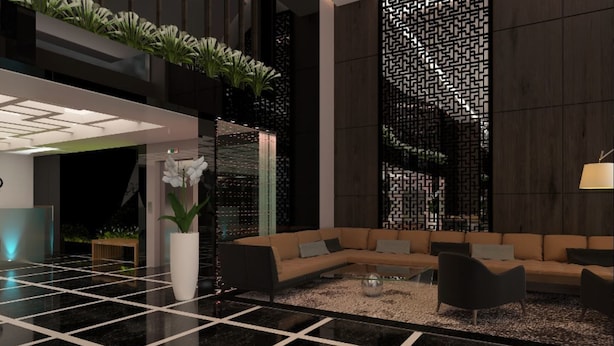 Un vestíbulo moderno con piso de baldosas blanco y negro, un sofá modular, una mesita de centro y una pared decorativa con un diseño geométrico.
