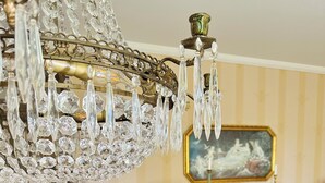 A dining area with a wooden table, chairs, a chandelier, a wooden cabinet, and a painting on the wall. - Aspa Herrg ård (Aspabruk)