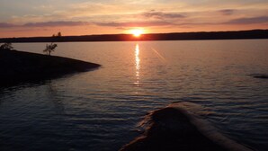 A sunset over a calm lake with a small island in the foreground. - Aspa Herrgård (Aspabruk)