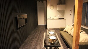 A modern kitchen with a dining area, a sofa, and a TV mounted on the wall. - SEKAI HOTEL Tsuki (Osaka)