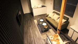 A compact living space with a kitchenette, a sofa, a coffee table, and a view of the outdoors. - SEKAI HOTEL Tsuki (Osaka)