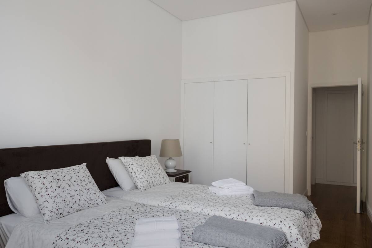 A bedroom with a bed, pillows, a nightstand, a lamp, and a wardrobe.