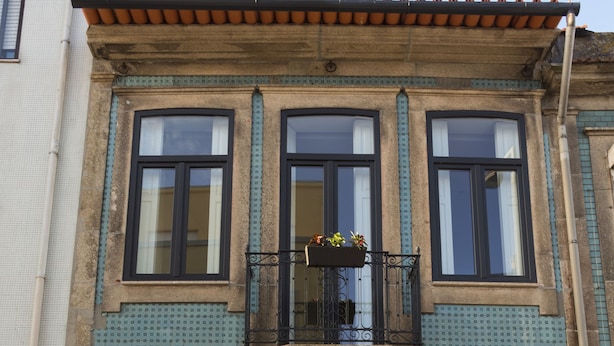 A building with a black door, large windows, and a balcony with potted plants. - Casa Velha Guesthouse (Porto)