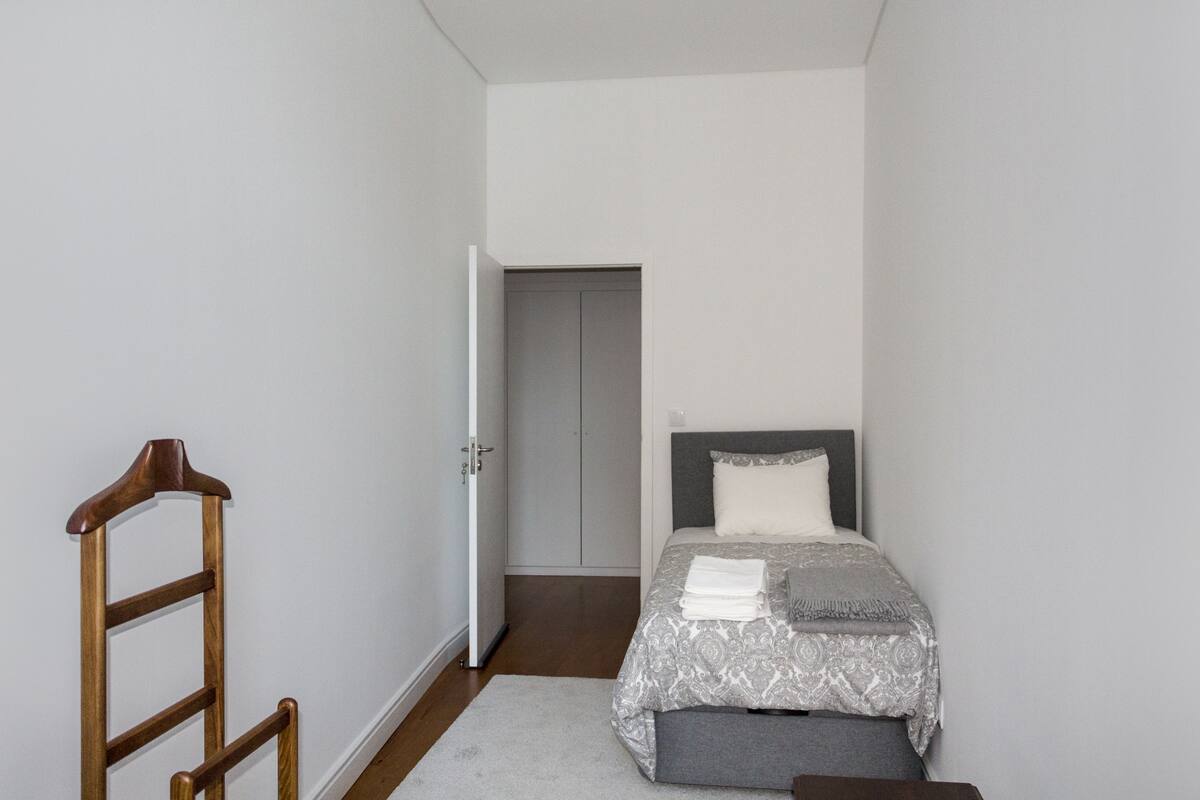 A bedroom with a bed, a wooden ladder, and a wardrobe.