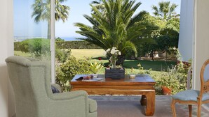 A room with a view of a lush garden and a body of water. - Bem Parece (Albufeira)