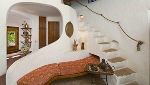 A cozy interior with a curved bench, a wooden staircase, and a rustic decor including a globe and pottery. - Bem Parece (Albufeira)