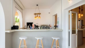 Une cuisine moderne dotée d’un coin bar, comprenant des tabourets de bar, une machine à café et diverses bouteilles.
