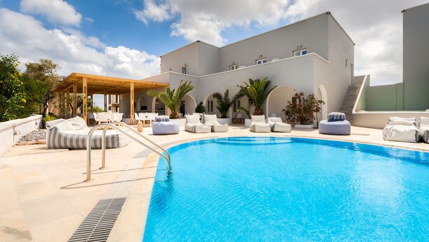 Une piscine avec des chaises longues et un espace de détente abrité.