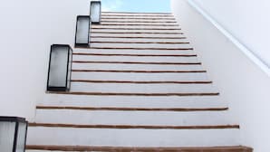 Un escalier menant à une fenêtre d’où l’on peut admirer un ciel bleu dégagé.
