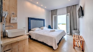 Une chambre d’hôtel moderne dotée d’un grand lit, d’une coiffeuse en bois avec un lavabo, d’un téléviseur à écran plat et offrant une vue sur l’extérieur.