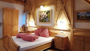 Een houten slaapkamer met een bed, een nachtkastje, een garderobe en een schilderij aan de muur.